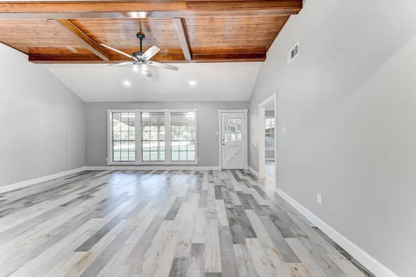 a view of an empty room with wooden floor and windows