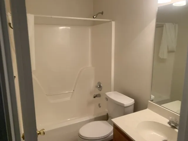 a white toilet sitting next to a bathroom sink and vanity