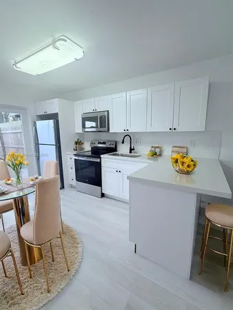 a kitchen with stainless steel appliances a stove a sink cabinets and a dining table