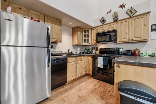 a kitchen with granite countertop a refrigerator stove and white cabinets