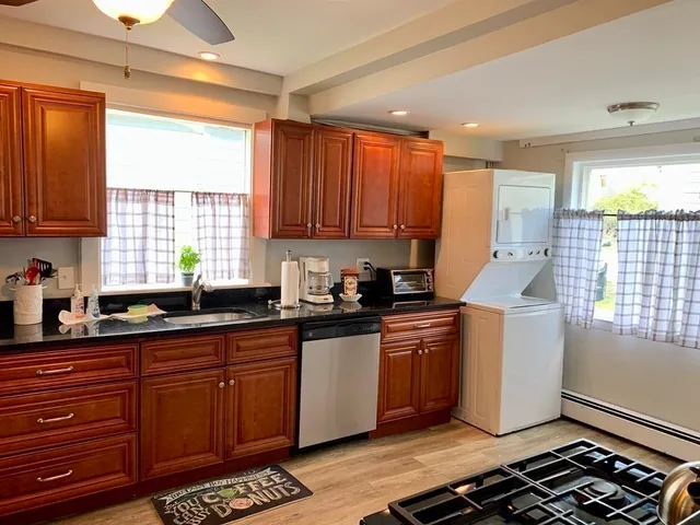 a kitchen with stainless steel appliances granite countertop a stove a sink dishwasher and cabinets with wooden floor