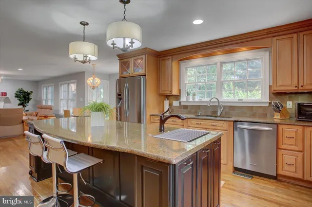 a kitchen with stainless steel appliances granite countertop a refrigerator a sink dishwasher a stove and white countertops with wooden floor