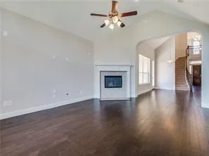 an empty room with wooden floor fireplace and windows