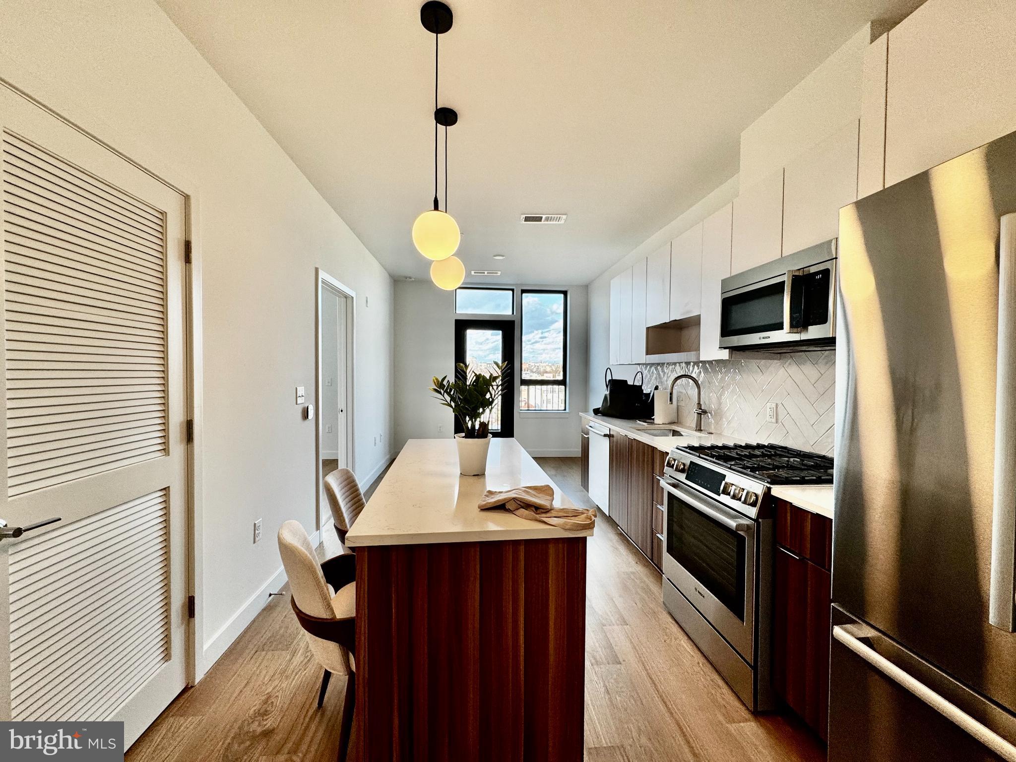 7175 12th Street Northwest, Unit 608 Washington, DC 20012 - Photo 6 of 24 a kitchen with stainless steel appliances a stove refrigerator sink and microwave