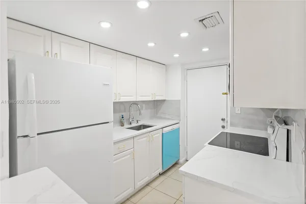a kitchen with a sink a refrigerator and white cabinets