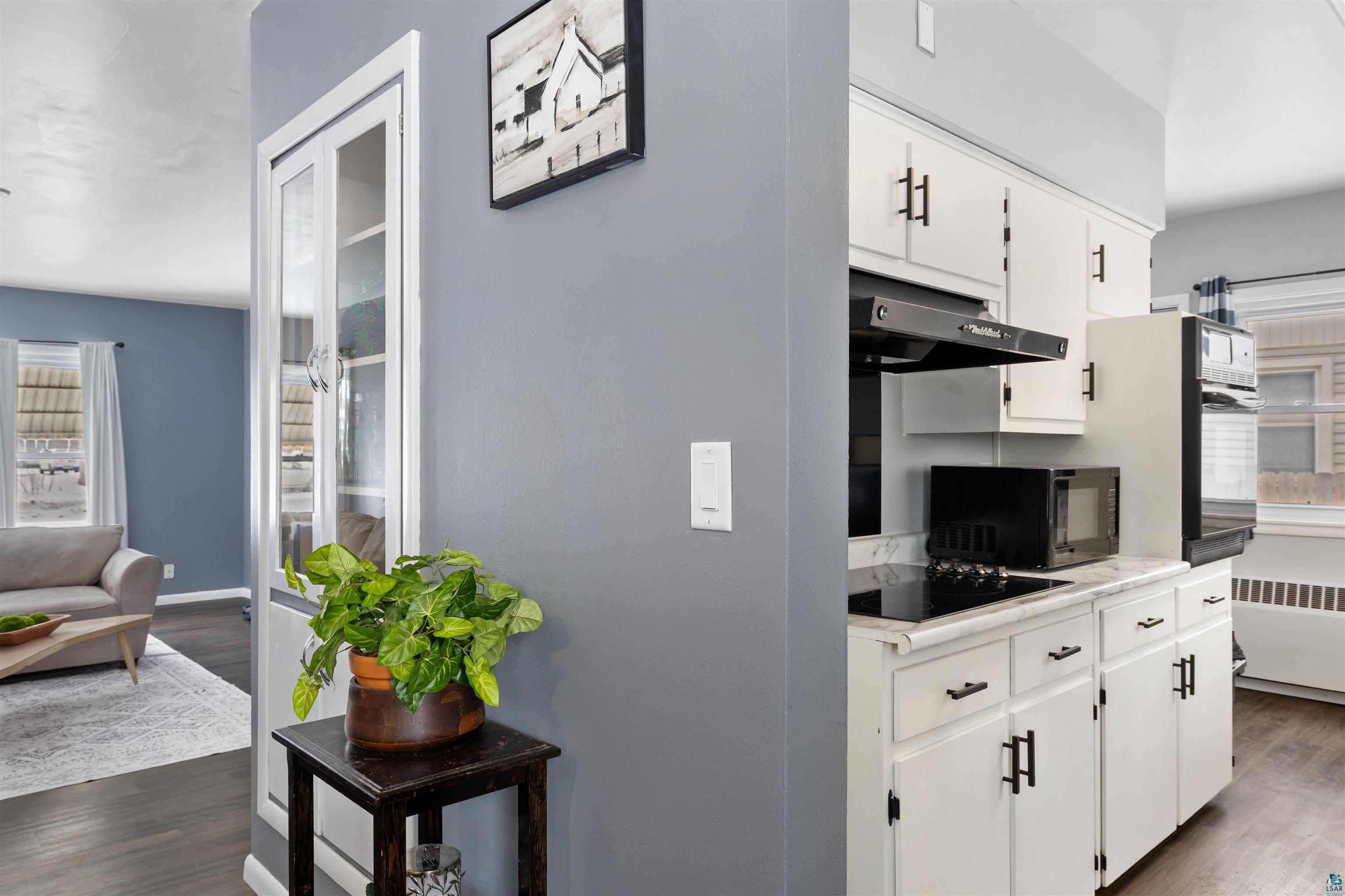1101 13th Street South Virginia, MN 55792 - Photo 15 of 43 Kitchen featuring dark laminate flooring, white cabinetry, black appliances, cooktop, wall oven, microwave and light laminate countertops