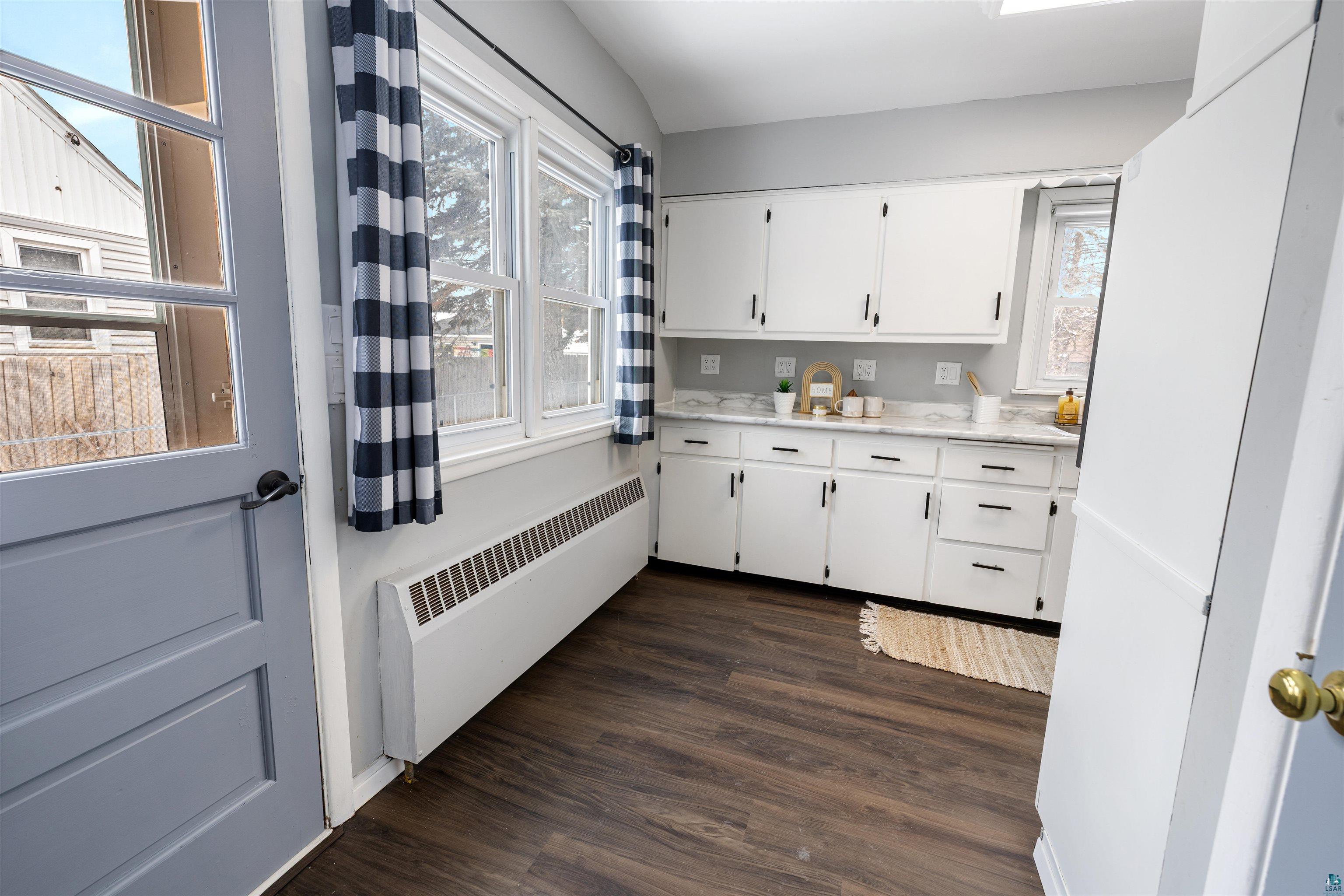 1101 13th Street South Virginia, MN 55792 - Photo 17 of 43 Kitchen featuring radiator, white cabinets, dark laminate floors, light stone countertops and access door to the sideyard
