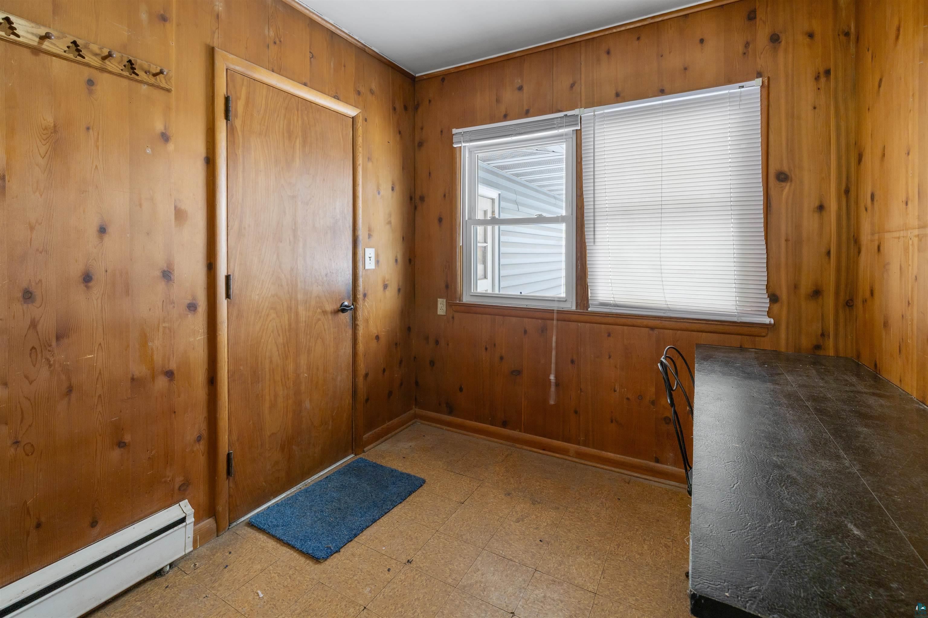1101 13th Street South Virginia, MN 55792 - Photo 30 of 43 Doorway to outside featuring tile patterned floors, a baseboard heating unit, and wood walls