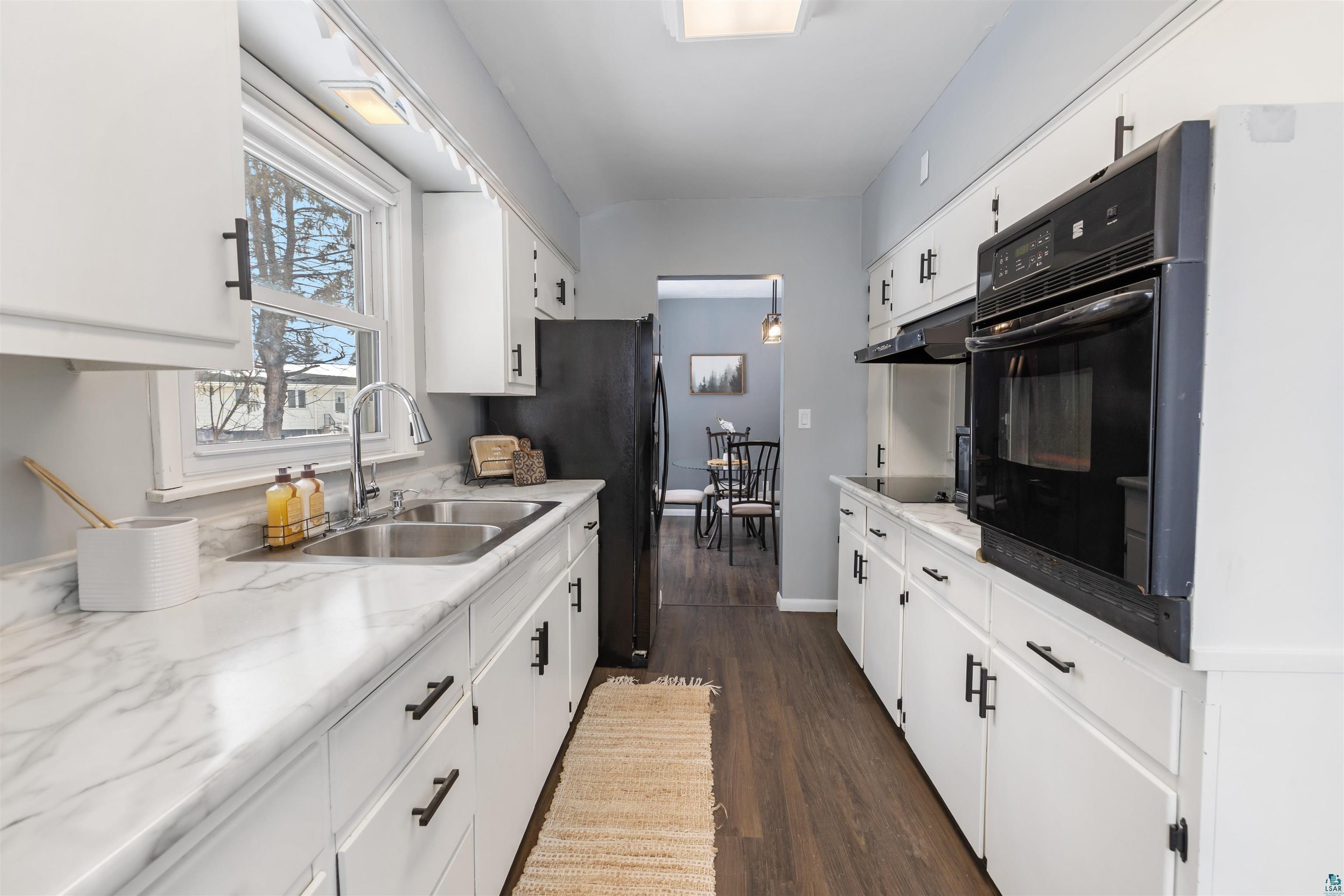 1101 13th Street South Virginia, MN 55792 - Photo 3 of 43 Kitchen featuring light laminate countertops, white cabinets, black appliances, and dark laminate flooring