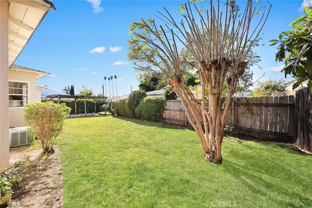 a view of backyard with wooden fence and trees