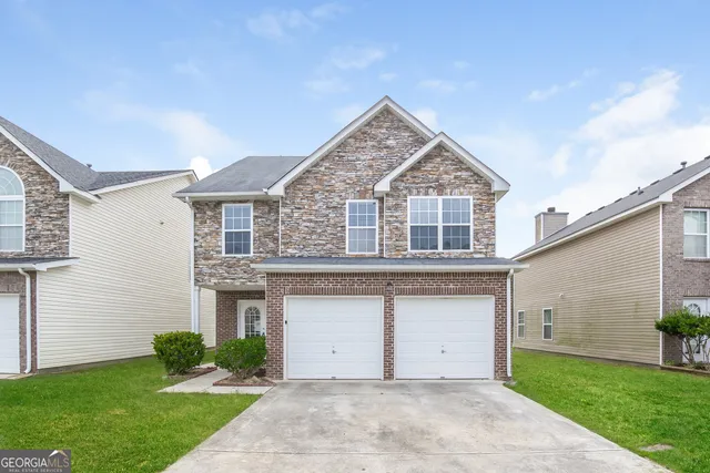 a front view of a house with a garden and garage