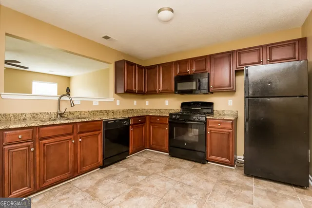 a kitchen with granite countertop a refrigerator stove top oven and sink