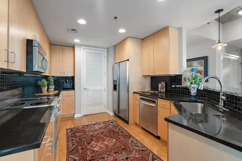 a kitchen with stainless steel appliances granite countertop a sink a stove top oven a chimney cabinets and a counter top space