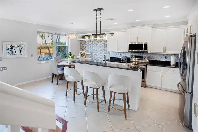 a kitchen with stainless steel appliances kitchen island granite countertop a sink and a refrigerator