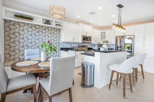 a dining room with furniture a chandelier and kitchen view
