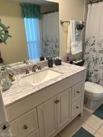 a bathroom with a granite countertop sink toilet and mirror