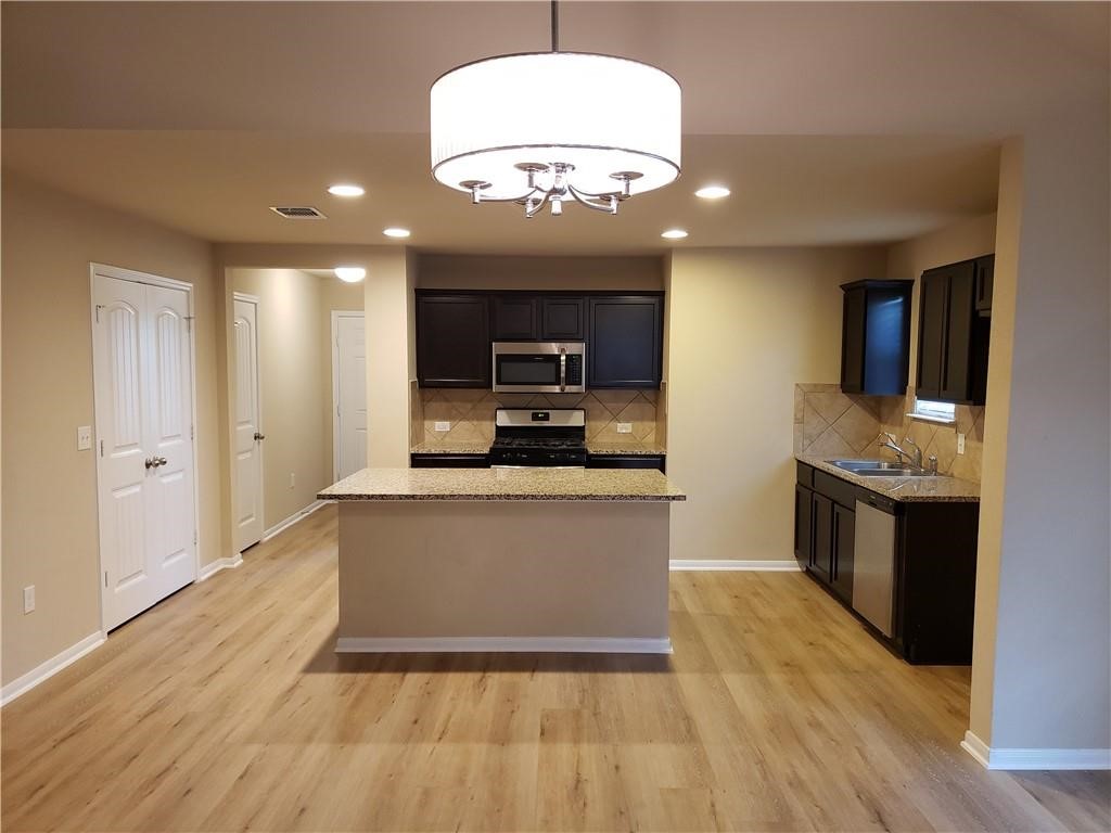 14909 Custis Lane Austin, TX 78725 - Photo 6 of 21 a large kitchen with kitchen island a sink dishwasher a refrigerator and a stove