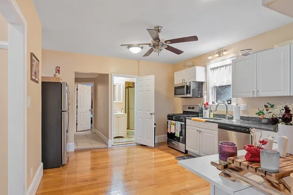 a kitchen with stainless steel appliances granite countertop a stove a sink and white cabinets