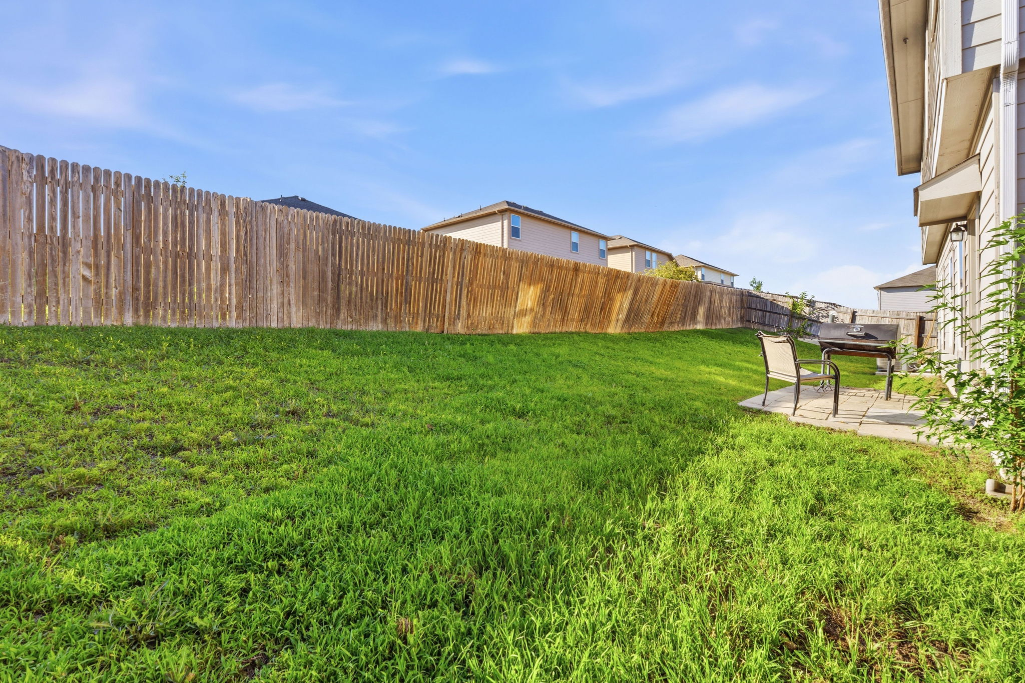 15101 Shell Bark Cove Austin, TX 78724 - Photo 24 of 26 Expansive grassy yard featuring a wood privacy fence, a concrete patio, and exterior siding