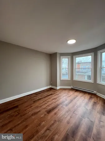 a view of an empty room with wooden floor and window
