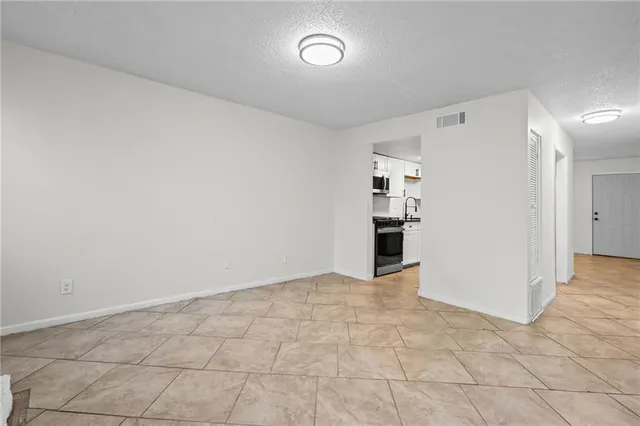 an empty room with kitchen view and entrance door