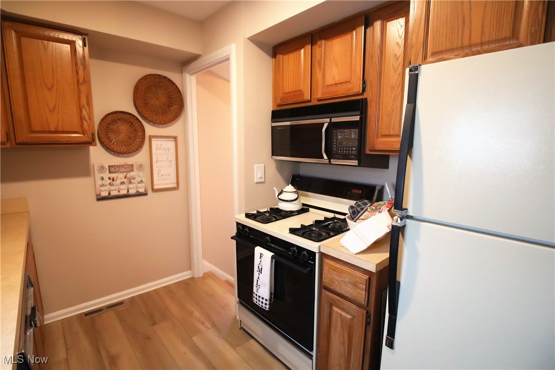 1344 Lander Road Cleveland, OH 44124 - Photo 8 of 49 Kitchen with freestanding refrigerator, range with gas stovetop, light wood-type flooring, light countertops, and brown cabinetry