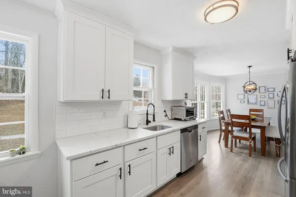 a kitchen with cabinets a sink dishwasher a dining table and chairs with wooden floor