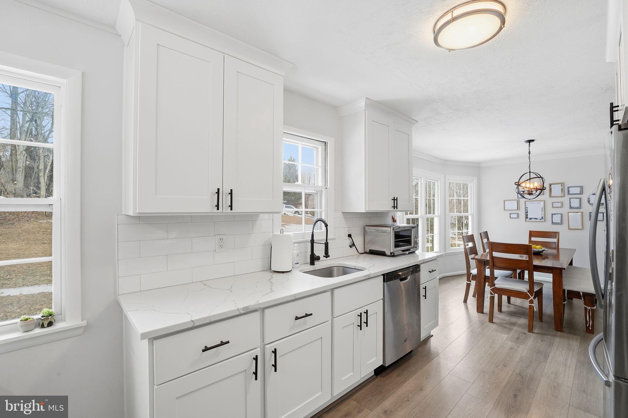 2207 Victor Court Silver Spring, MD 20906 - Photo 12 of 40 a kitchen with cabinets a sink dishwasher a dining table and chairs with wooden floor