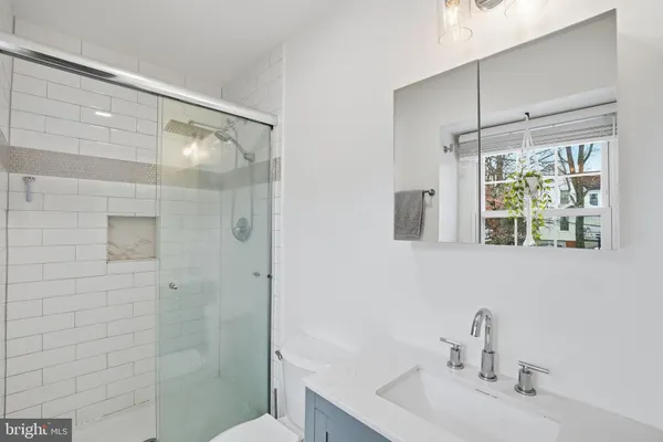 a bathroom with a sink a mirror a window and a shower