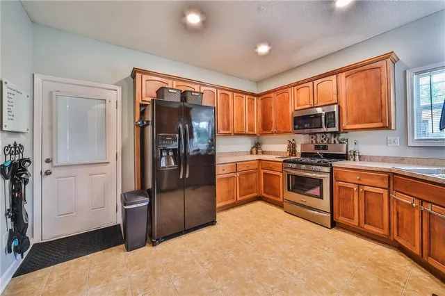 a kitchen with granite countertop a refrigerator and a stove top oven