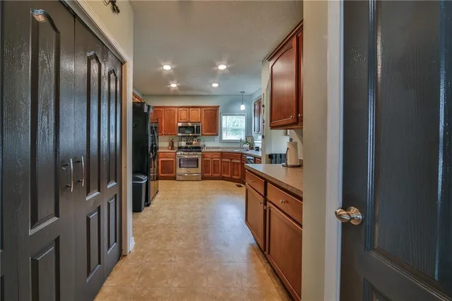 a large kitchen with stainless steel appliances granite countertop a refrigerator and a sink