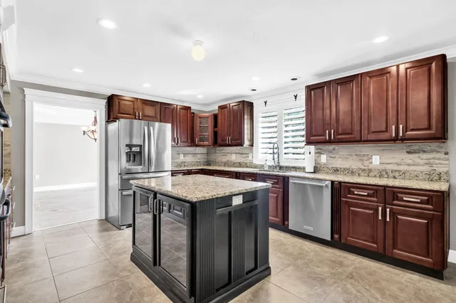 a view of an empty room with a window and kitchen view