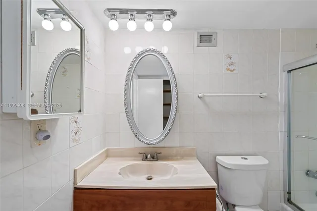 a bathroom with a sink a mirror a toilet and shower