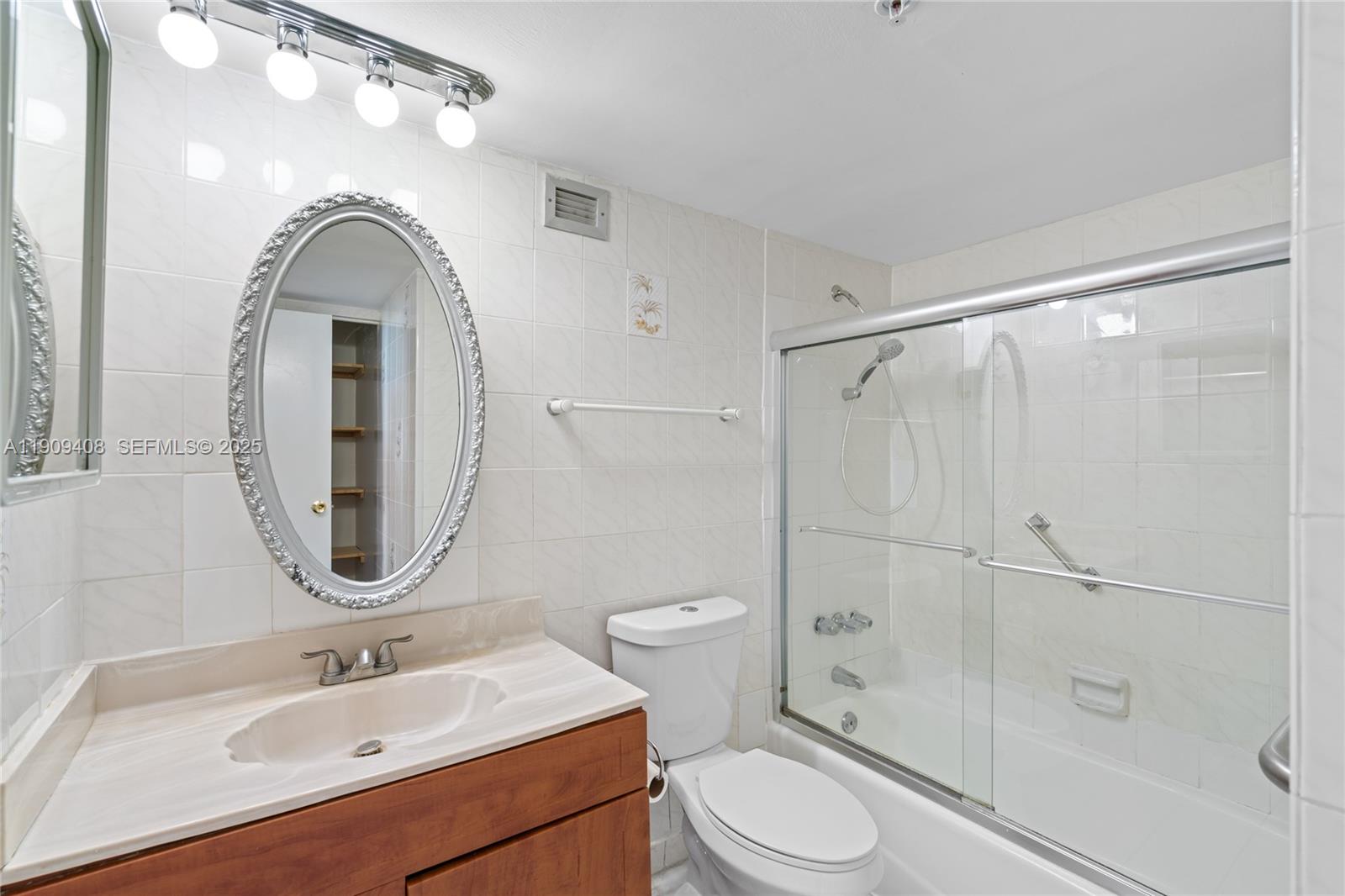 4101 Pine Tree Drive, Unit 802 Miami Beach, FL 33140 - Photo 20 of 58 a bathroom with a sink a mirror a toilet and shower
