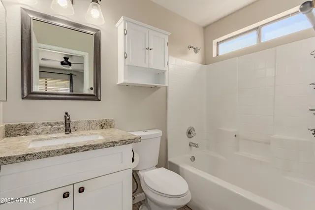 a bathroom with a granite countertop sink a toilet and a bathtub