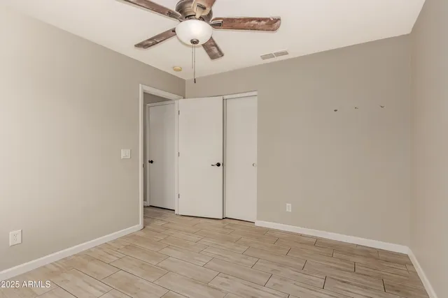 an empty room with a chandelier fan and a ceiling fan