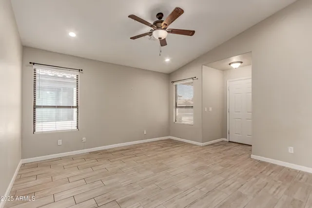 an empty room with chandelier fan and windows
