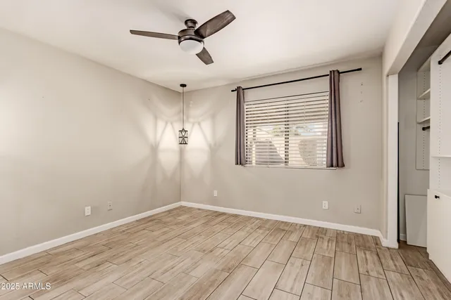 a view of empty room with wooden floor and fan