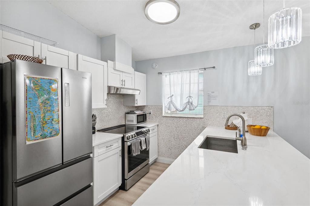 311 Poinsettia Road Anna Maria, FL 34216 - Photo 12 of 36 a kitchen with stainless steel appliances a refrigerator a sink a stove and white cabinets