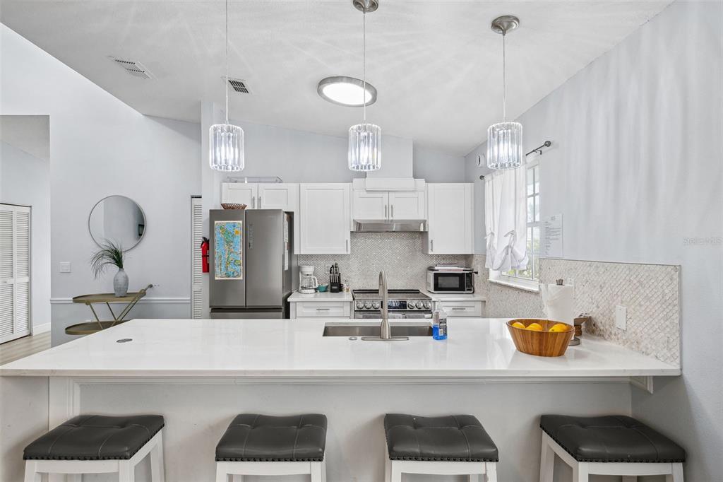 311 Poinsettia Road Anna Maria, FL 34216 - Photo 14 of 36 a kitchen with stainless steel appliances kitchen island granite countertop a sink a stove and white cabinets