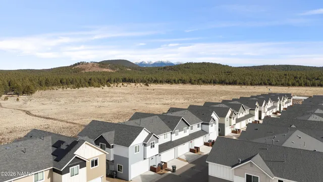 a view of a white house with large windows and couches in front of house