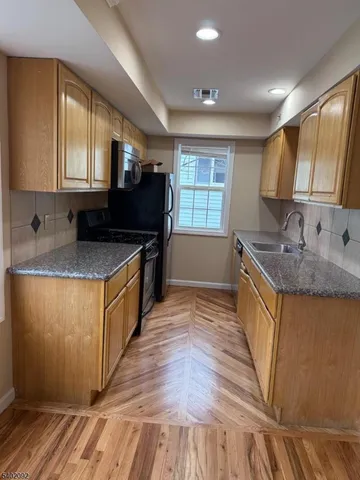 a kitchen with stainless steel appliances granite countertop a sink a stove and a wooden floors