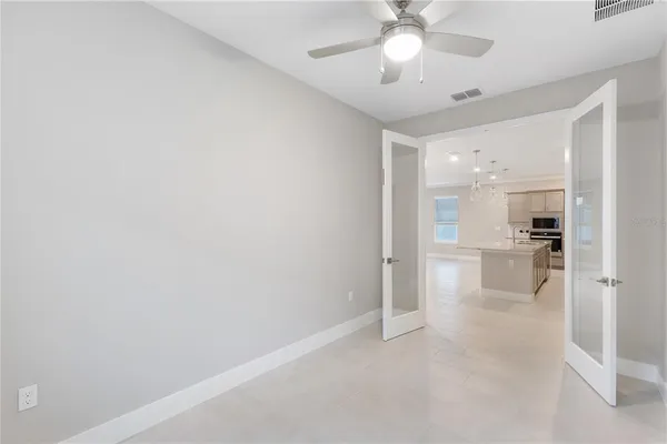 an empty room with a kitchen and a ceiling fan