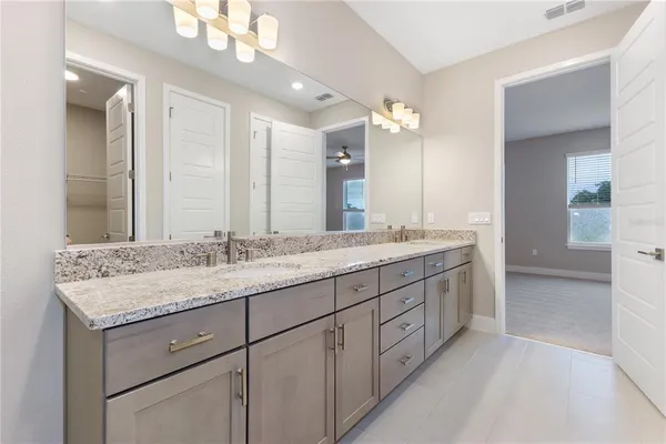 a bathroom with a granite countertop double vanity sink and a mirror
