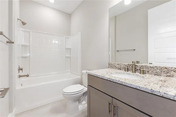 a bathroom with a granite countertop sink a toilet and bathtub