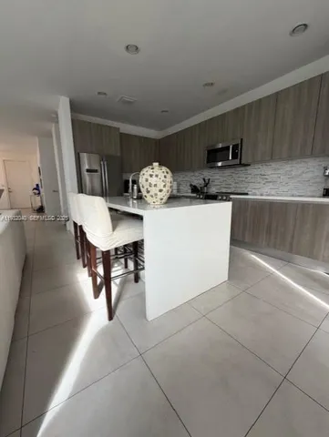 a room with stainless steel appliances kitchen island granite countertop a sink and cabinets
