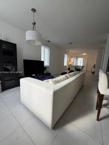 a living room with furniture a flat screen tv and kitchen view