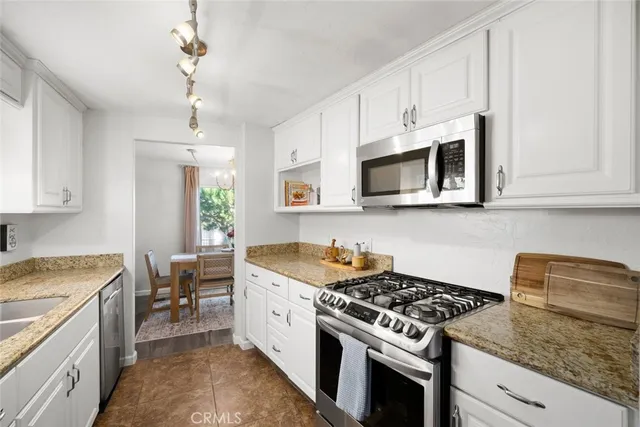 a kitchen with stainless steel appliances granite countertop a sink stove oven and white cabinets