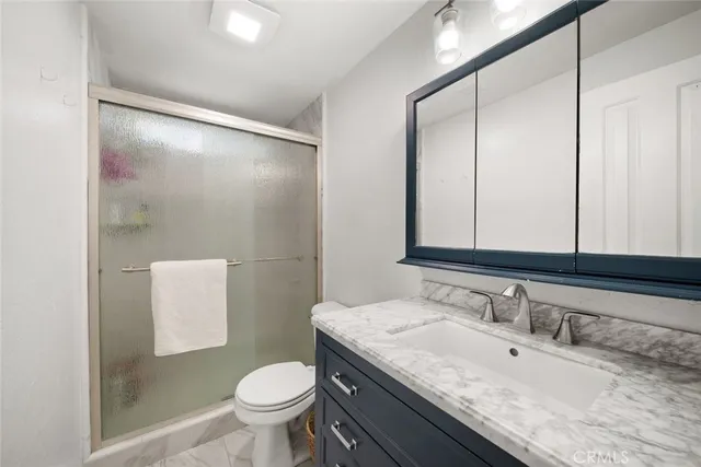 a bathroom with a granite countertop sink toilet and shower
