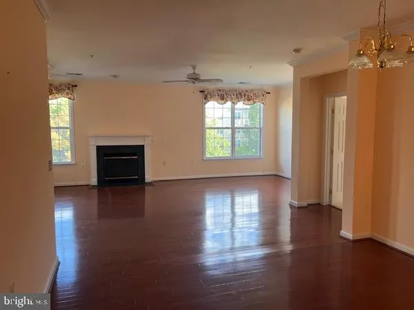 an empty room with wooden floor fireplace and windows
